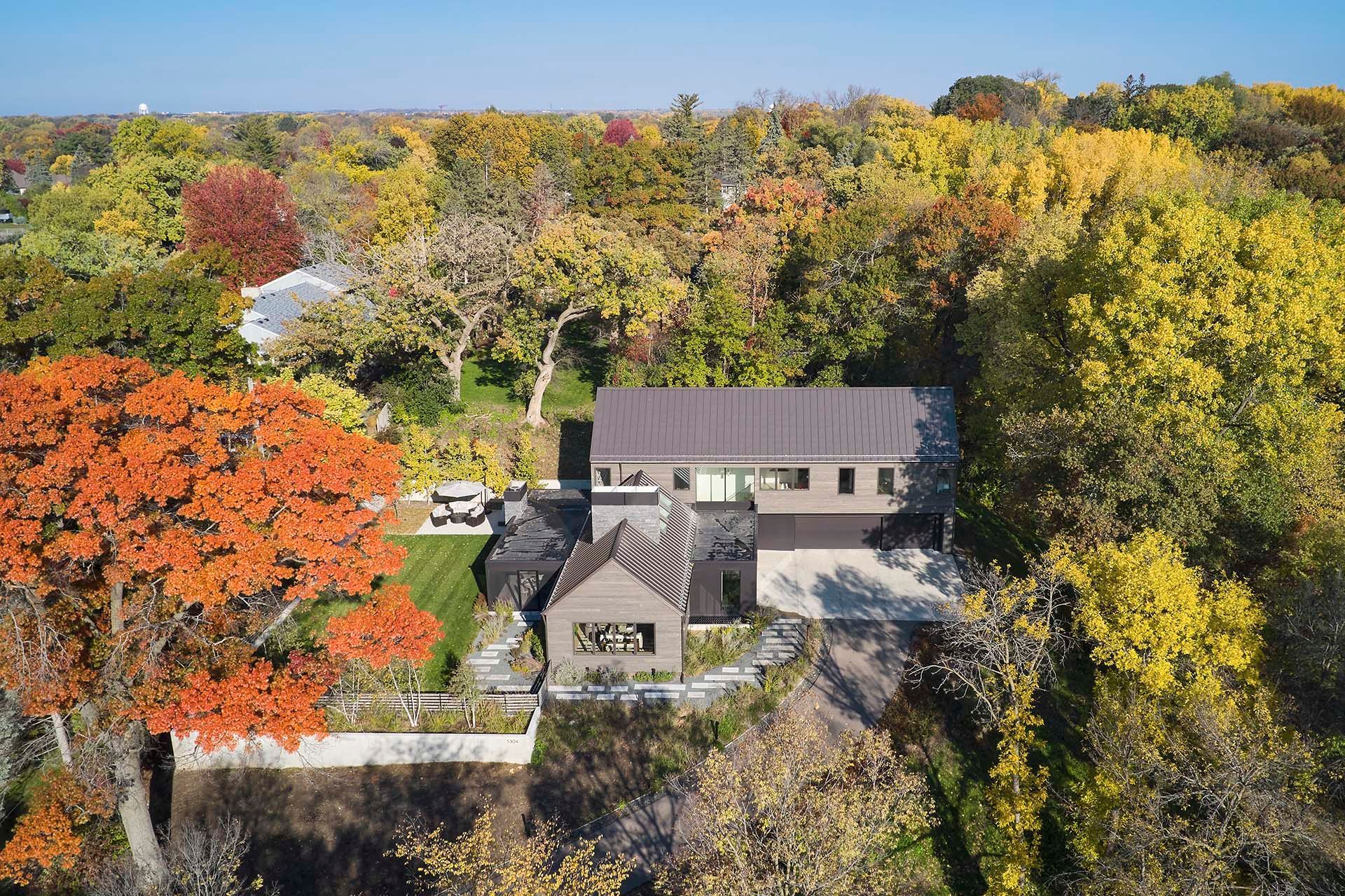An aerial view of a house surrounded by trees in the middle of a forest.