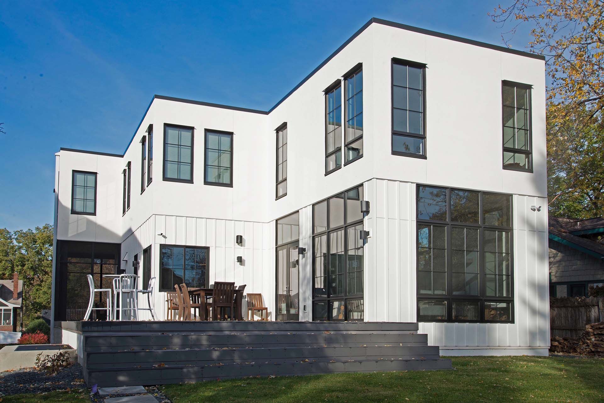A large white house with a lot of windows is sitting on top of a lush green field.