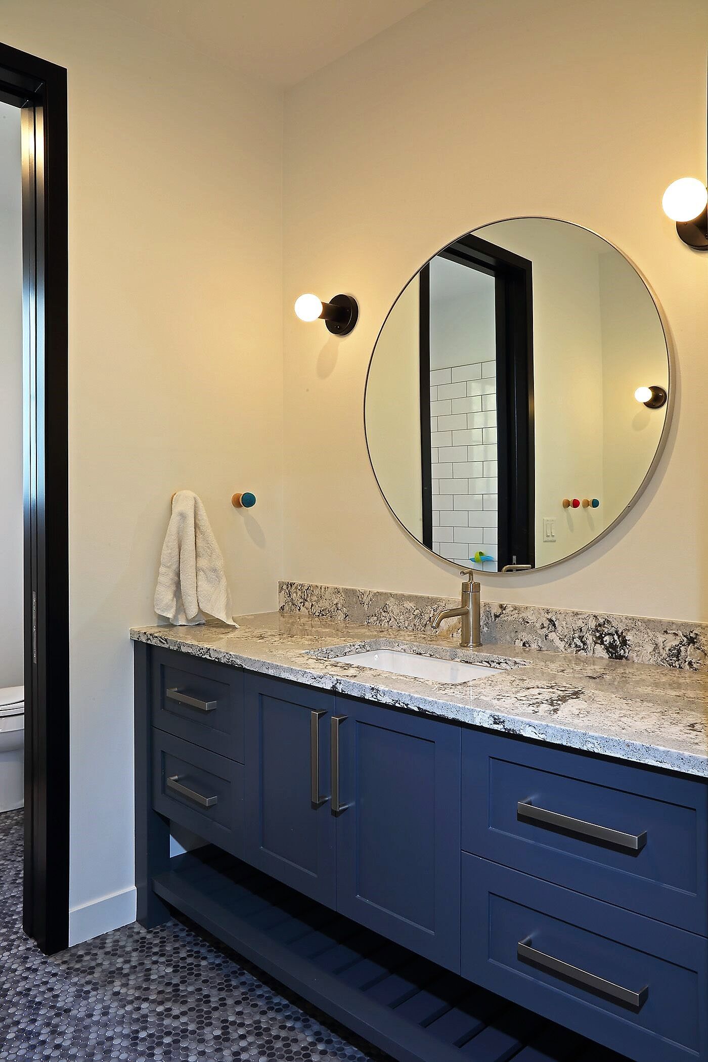 A bathroom with two sinks and a round mirror.