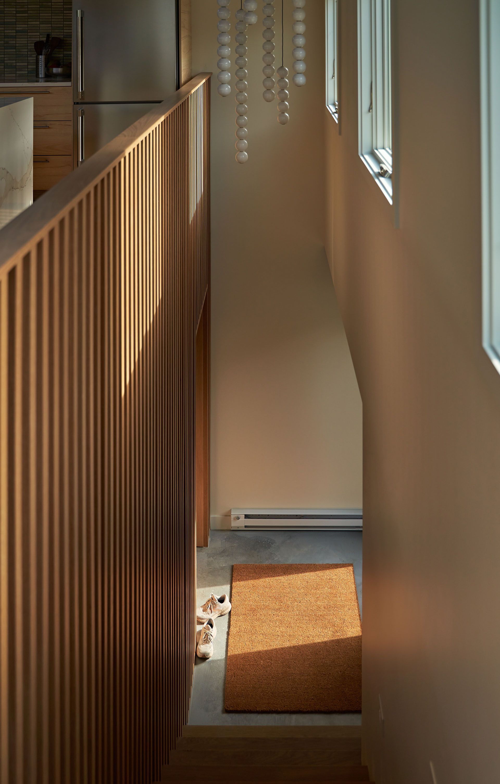 A hallway in a house with a wooden railing and a rug on the floor.
