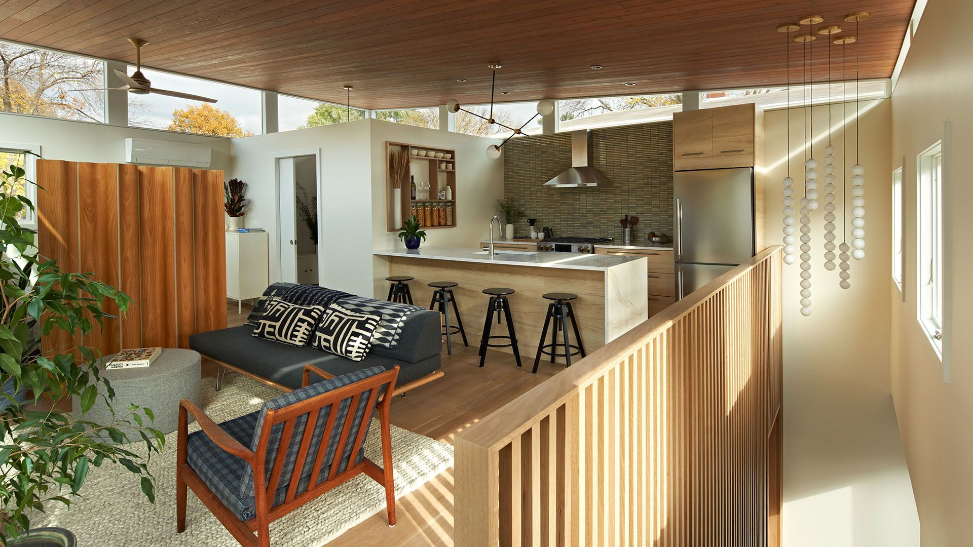 A living room with a couch and chairs and a kitchen