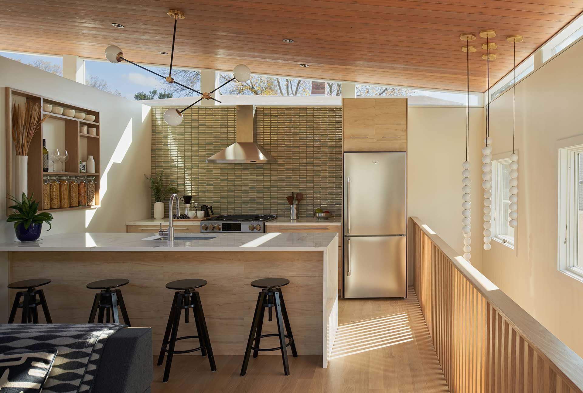 A kitchen with a stainless steel refrigerator , sink , and stools.