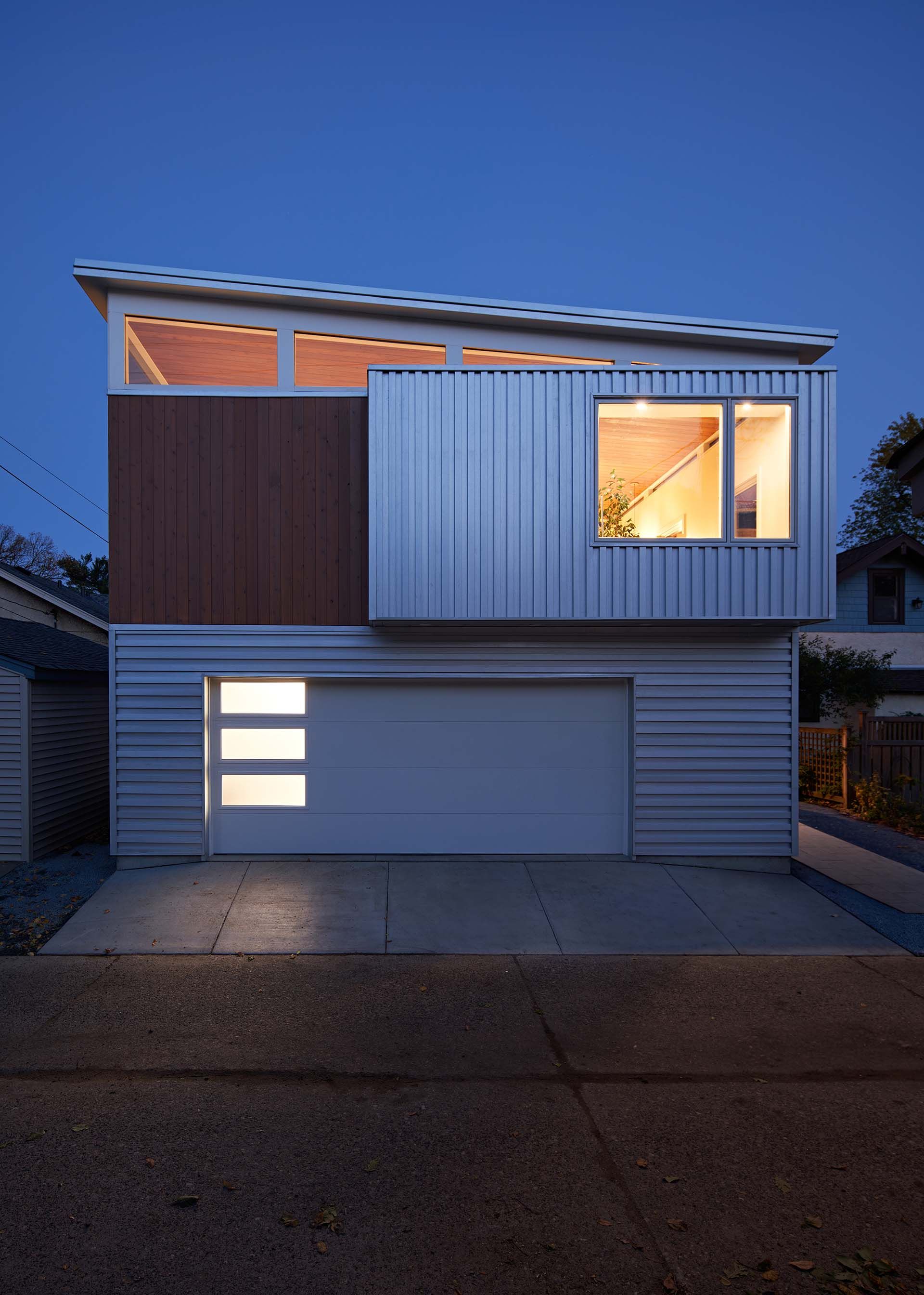 A modern house with a white garage door is lit up at night