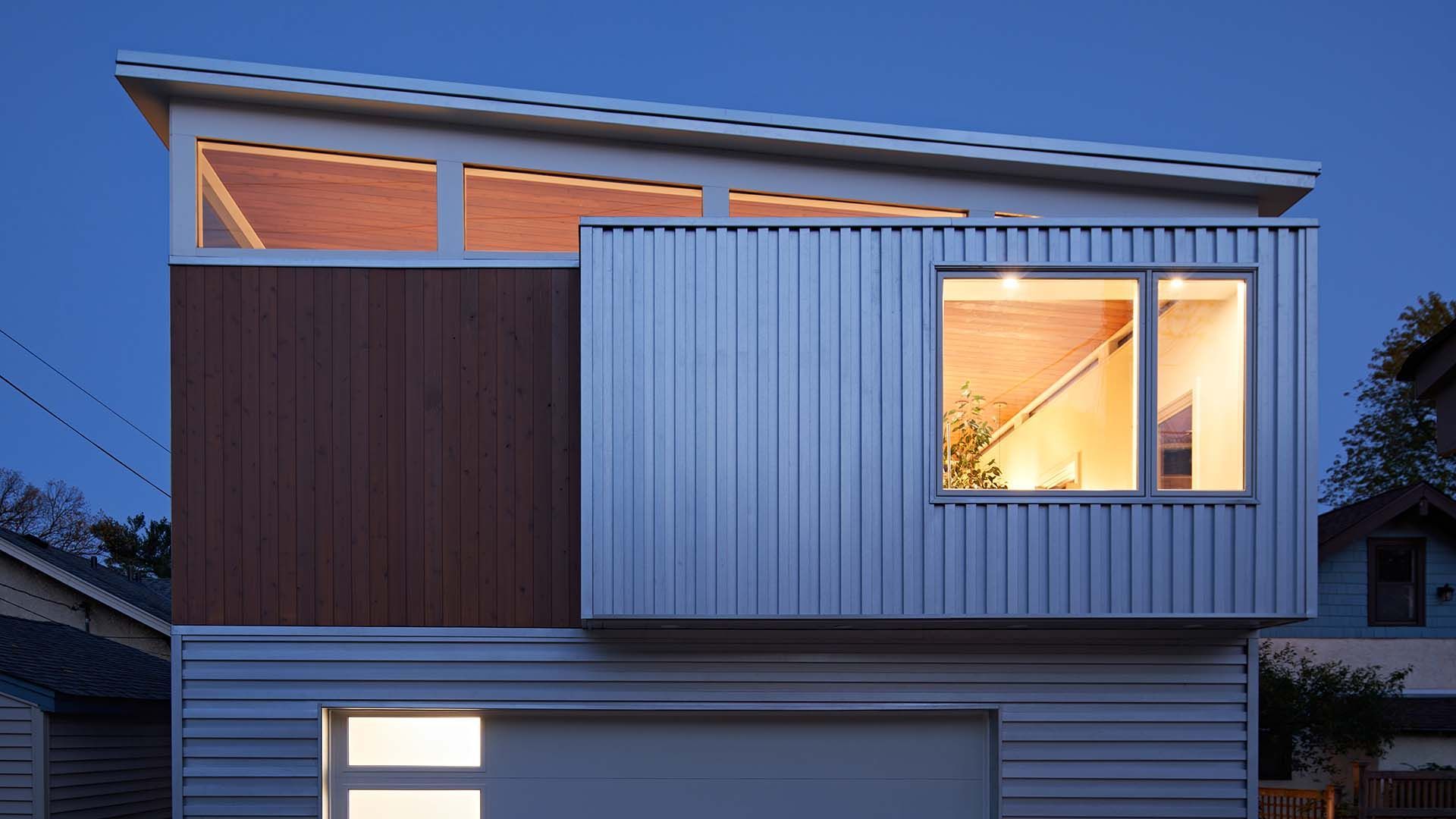 A house with a garage and a balcony is lit up at night
