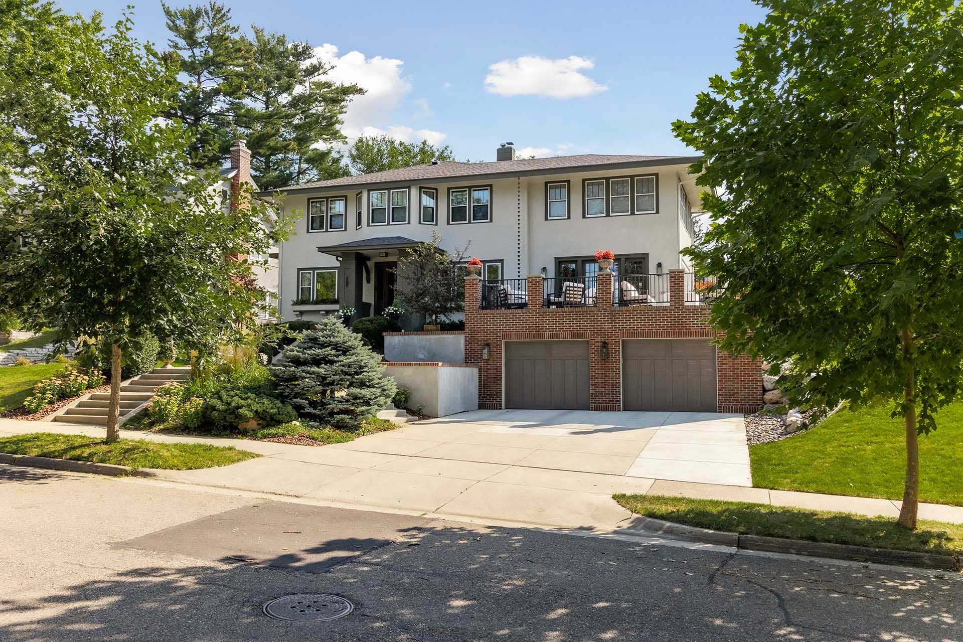 A large white house is surrounded by trees and a driveway.