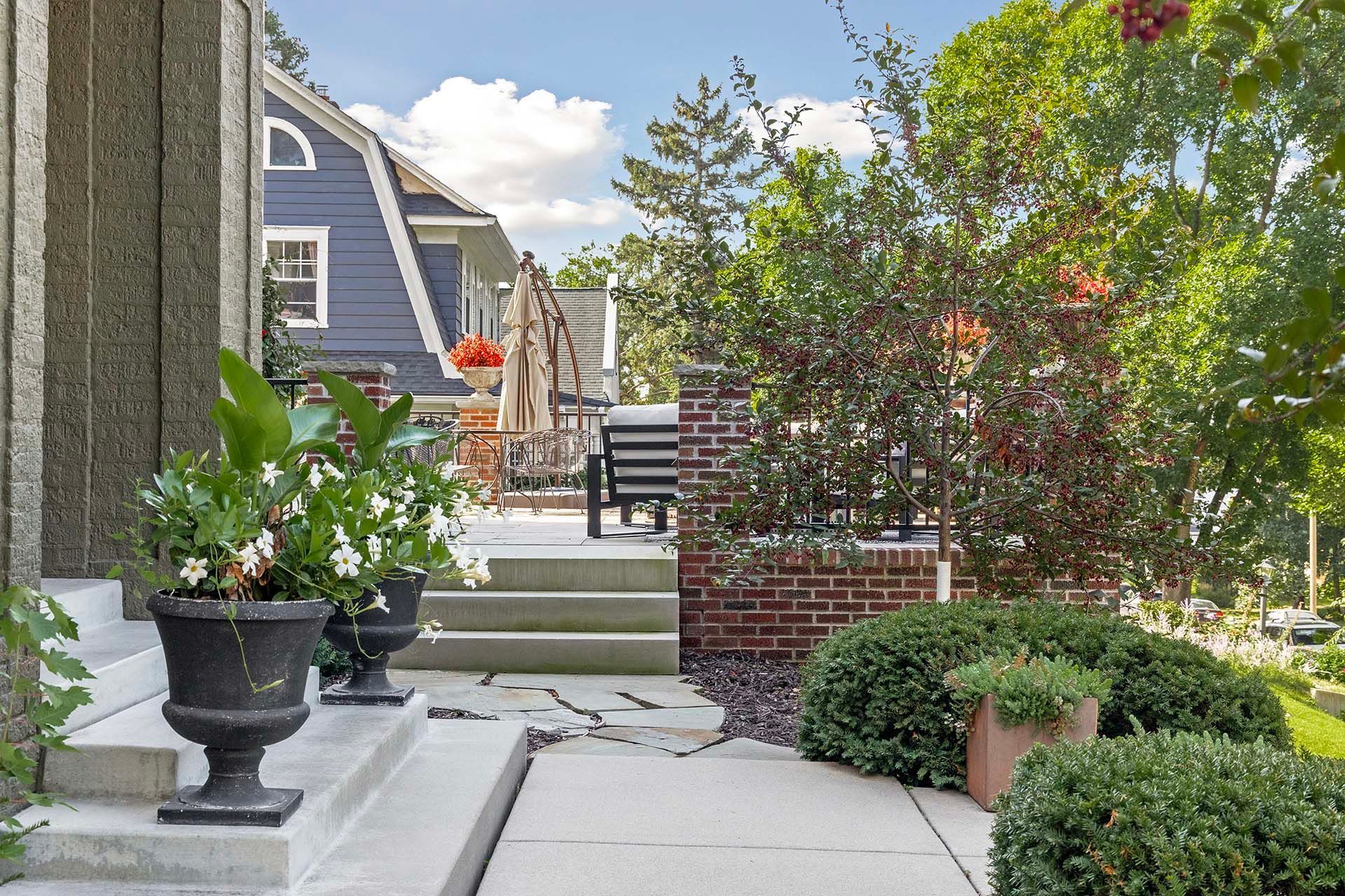 A walkway leading to a patio with a blue house in the background.