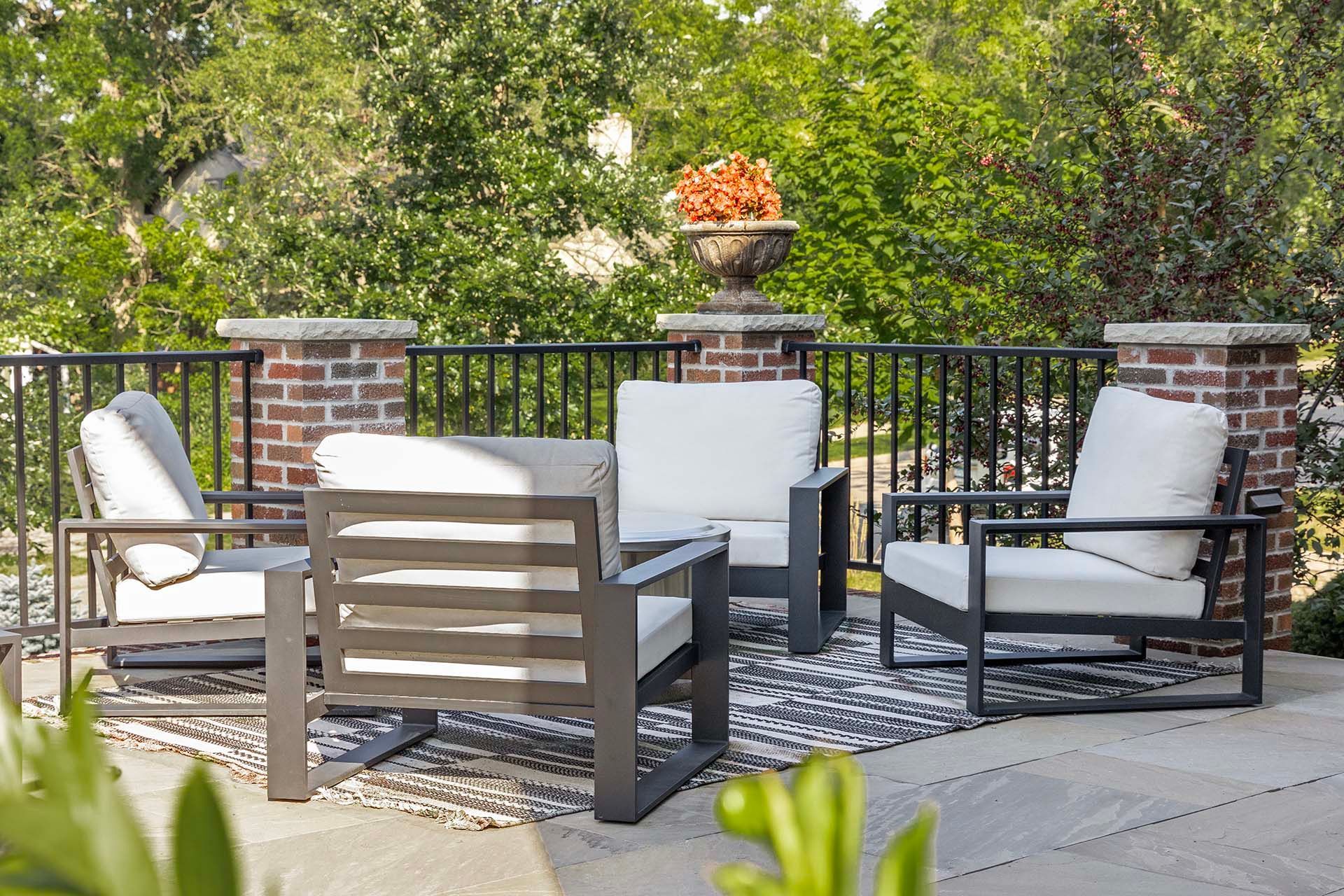 A patio with a couch , two chairs , and a table.