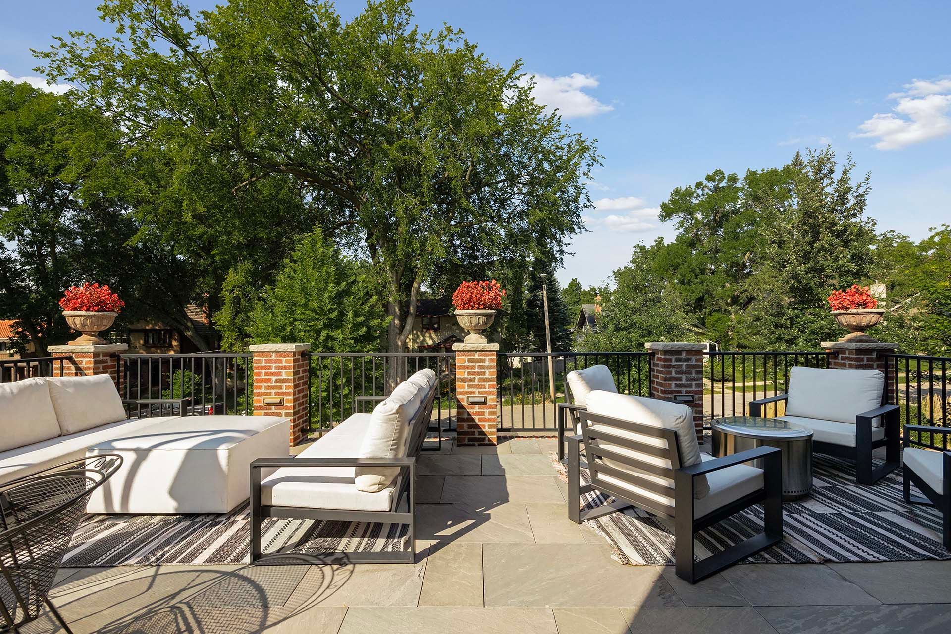 A patio with a lot of furniture and trees in the background.