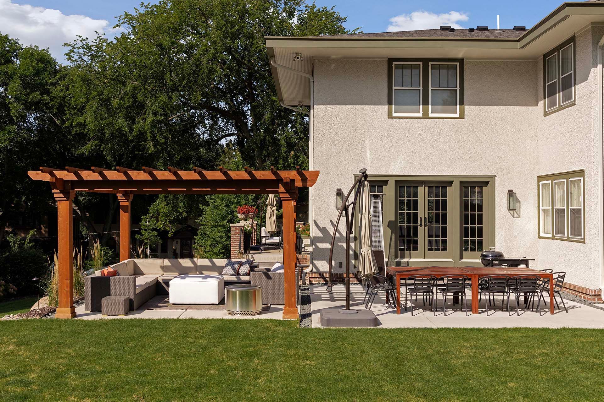 The backyard of a house with a pergola and patio furniture