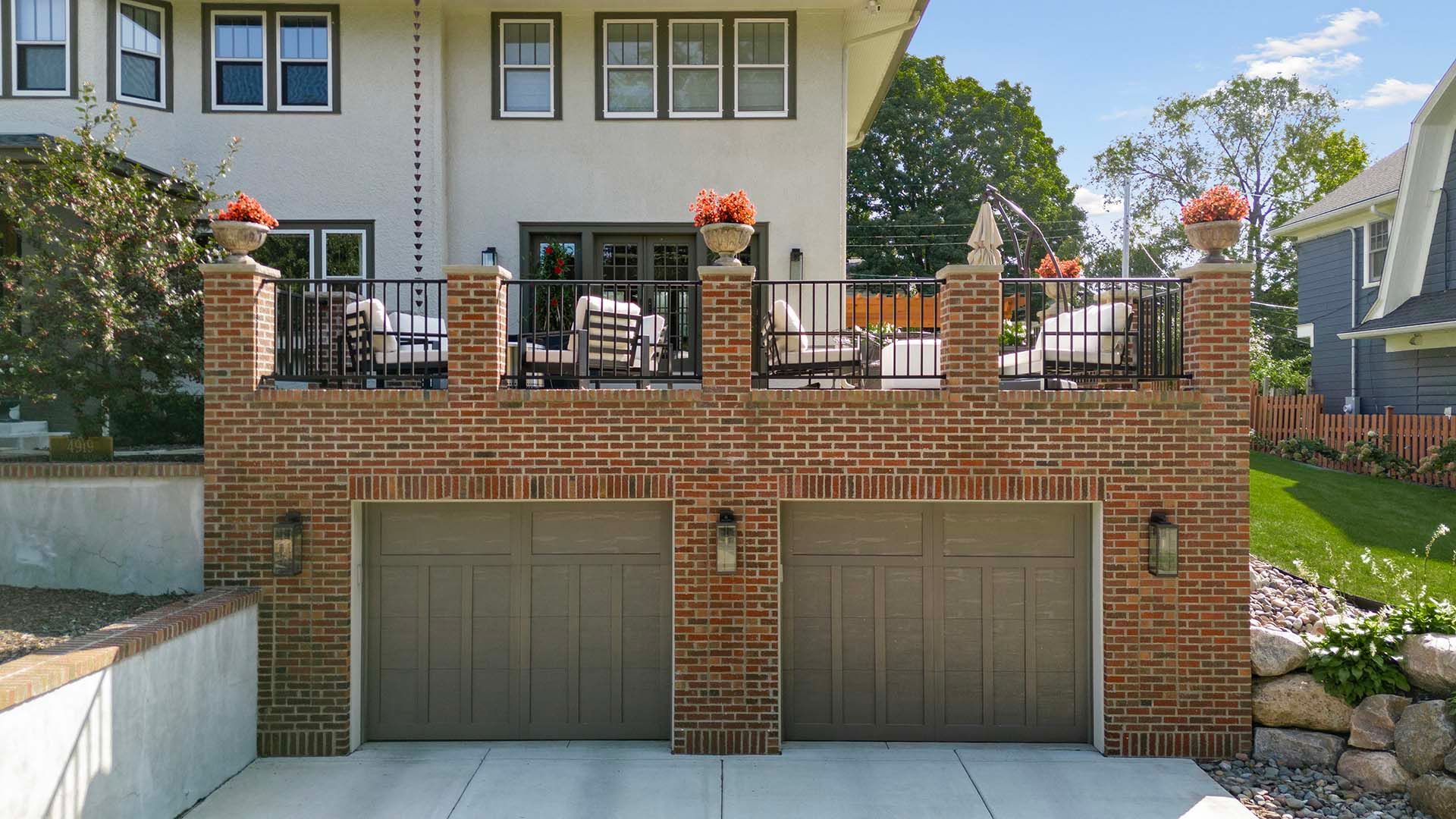 A large white house with two garage doors and a balcony.