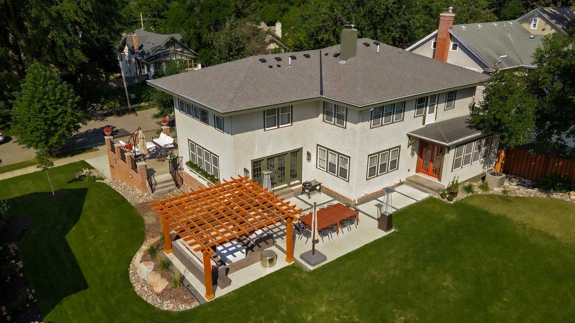 An aerial view of a large house with a pergola in the backyard.