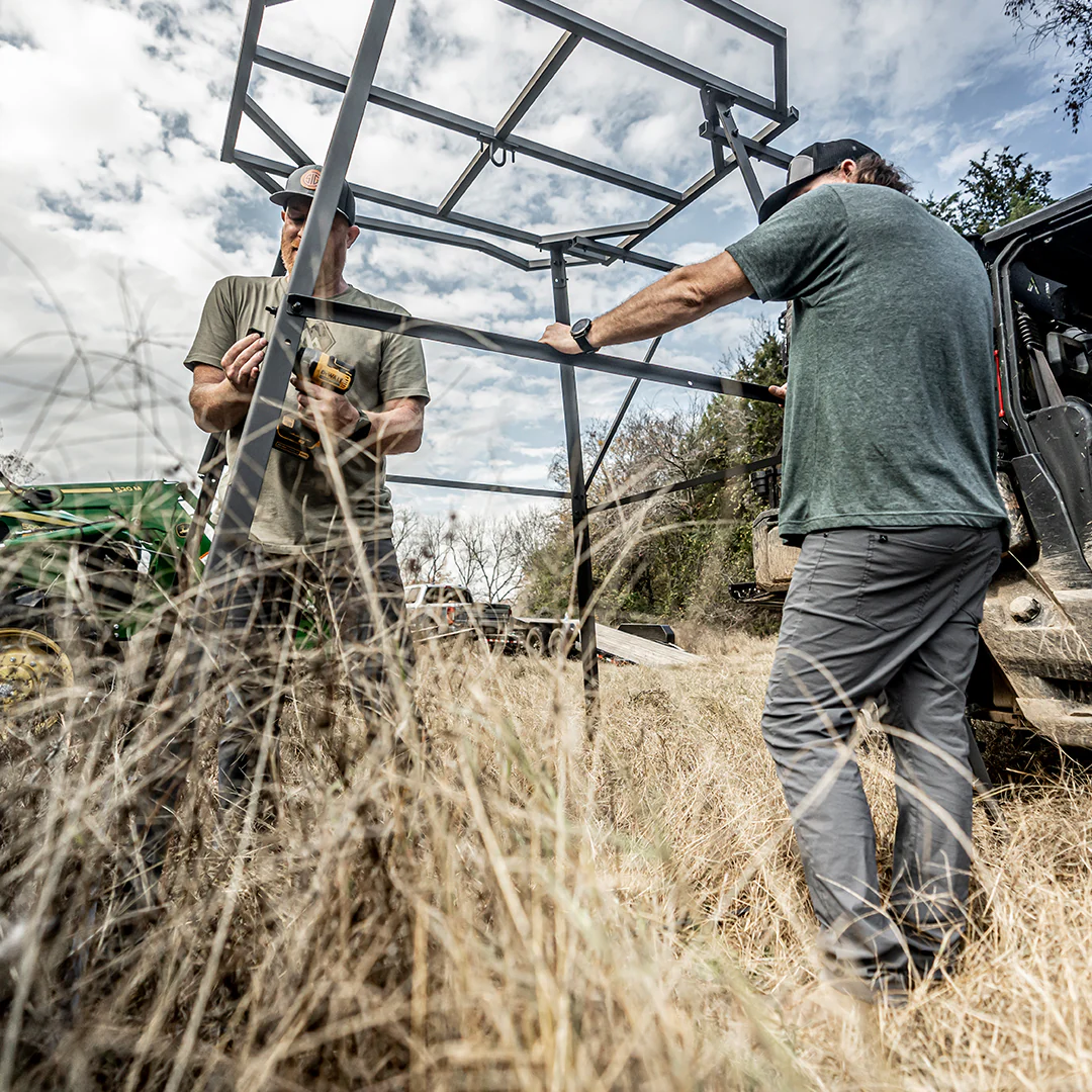A green hunting blind is sitting in the middle of a dry grass field.