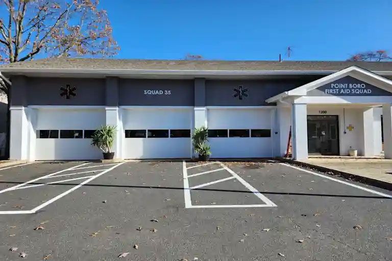 A building with three garage doors and a parking lot in front of it.