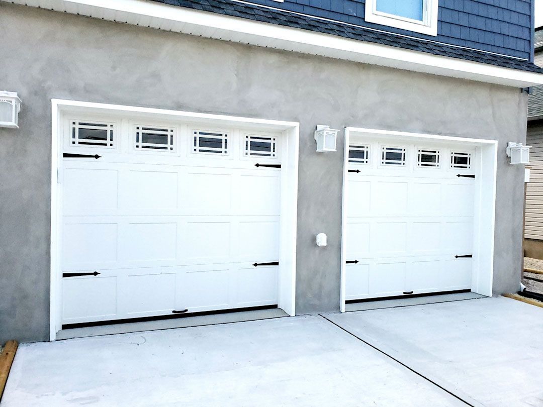 Two white garage doors are on the side of a house.