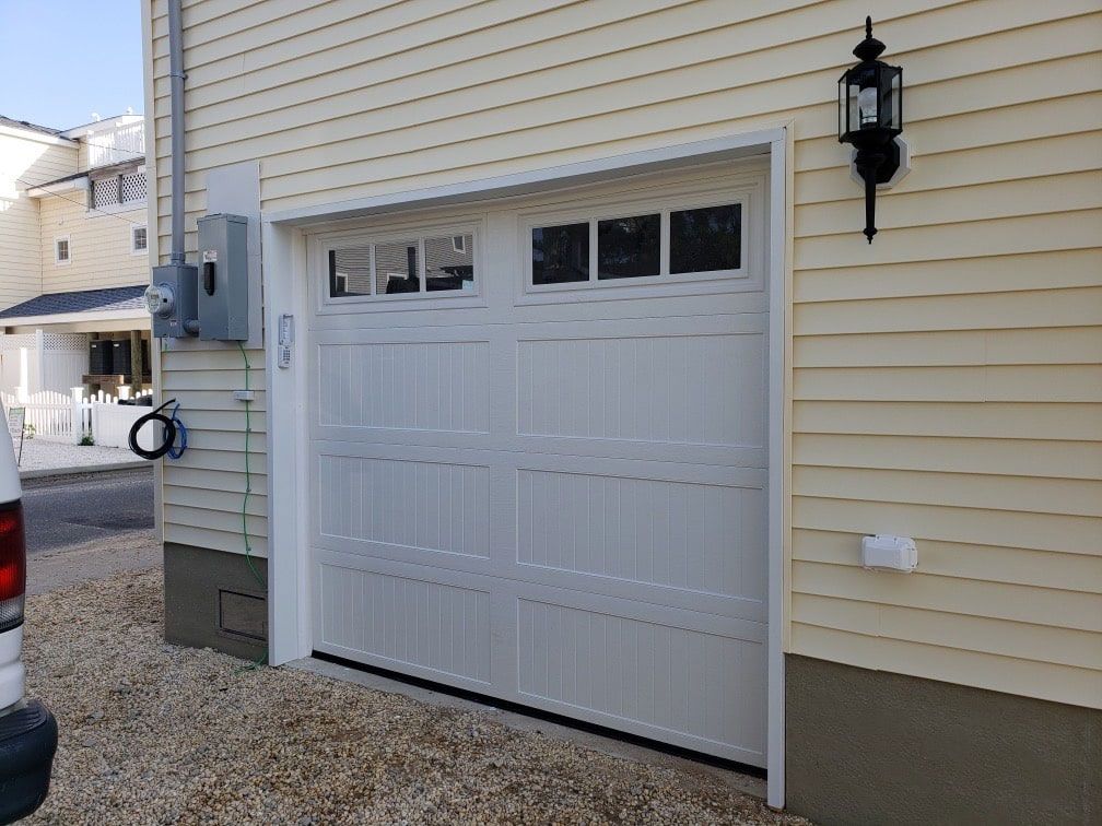 A white garage door is on the side of a house.