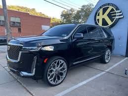 A black cadillac escalade is parked in a parking lot in front of a building.