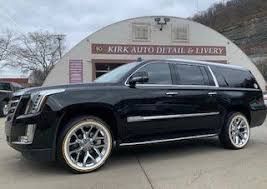 A black cadillac escalade is parked in front of a building.