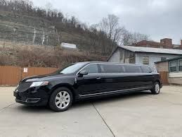 A black limousine is parked in a parking lot in front of a building.