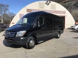 A black mercedes benz sprinter van is parked in front of a building.