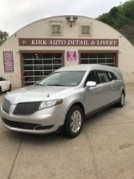 A silver limousine is parked in front of a building.