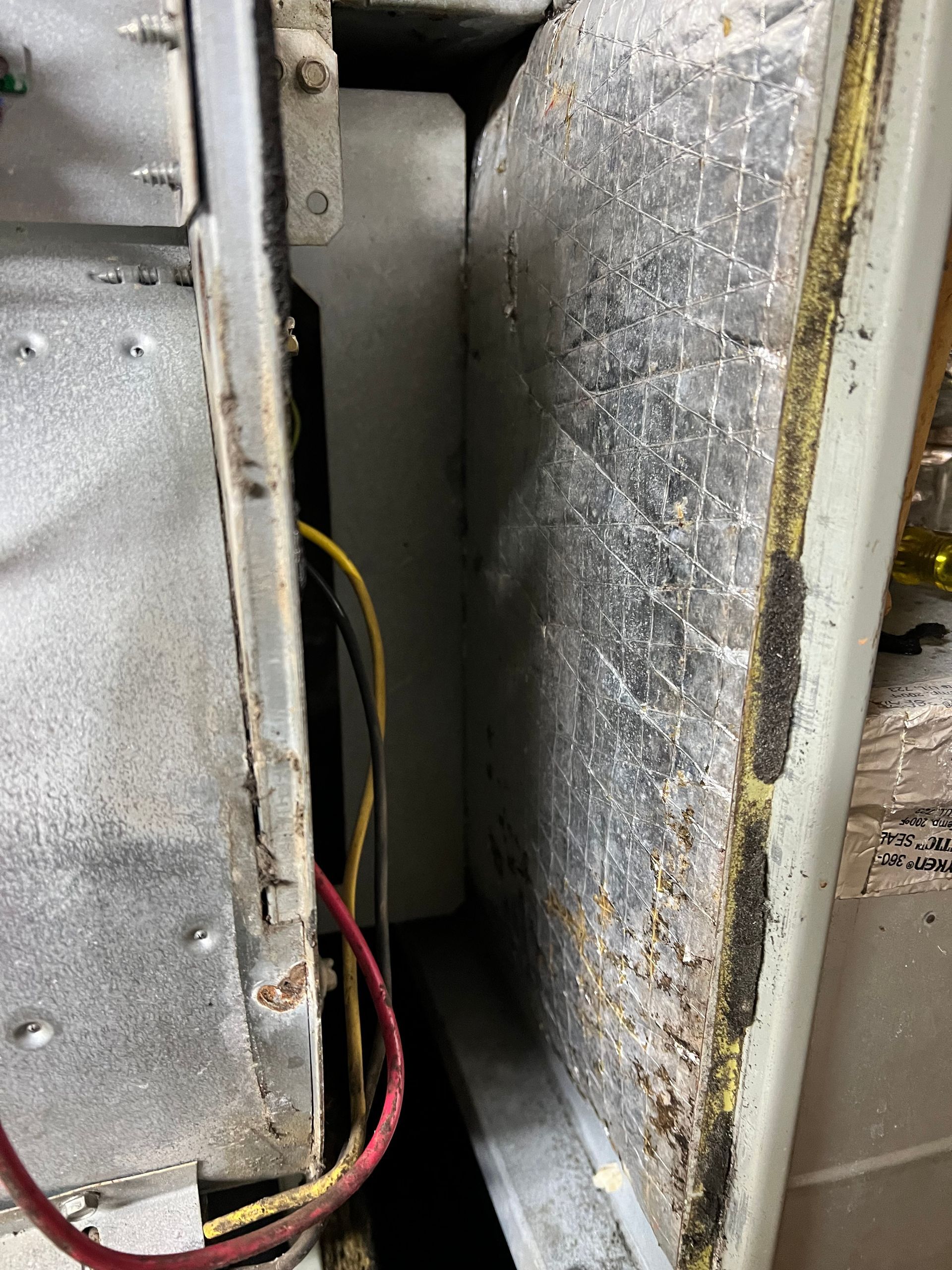 A close up of a dirty refrigerator door with wires coming out of it.