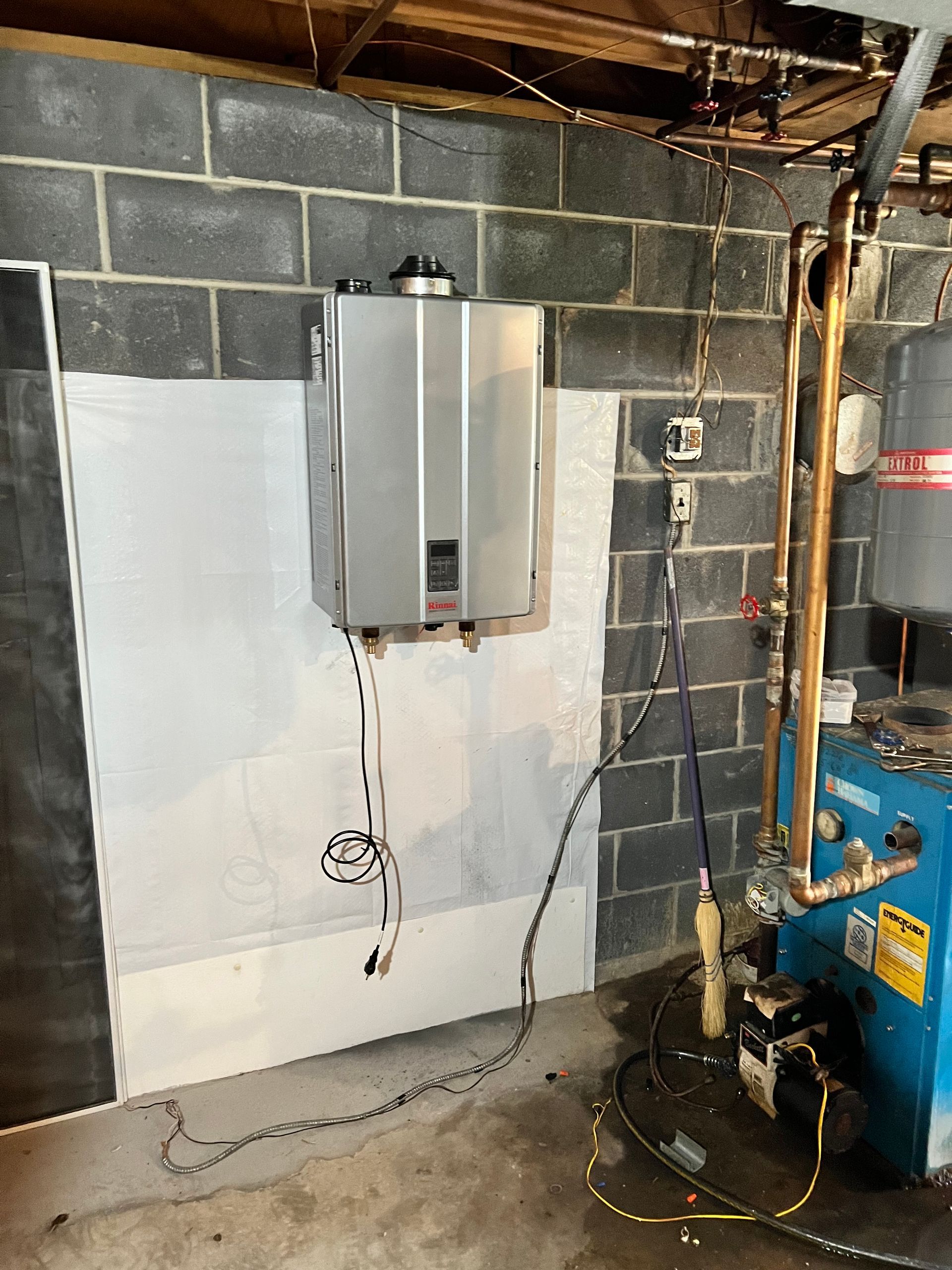 A blue boiler is sitting in a basement next to a water heater.