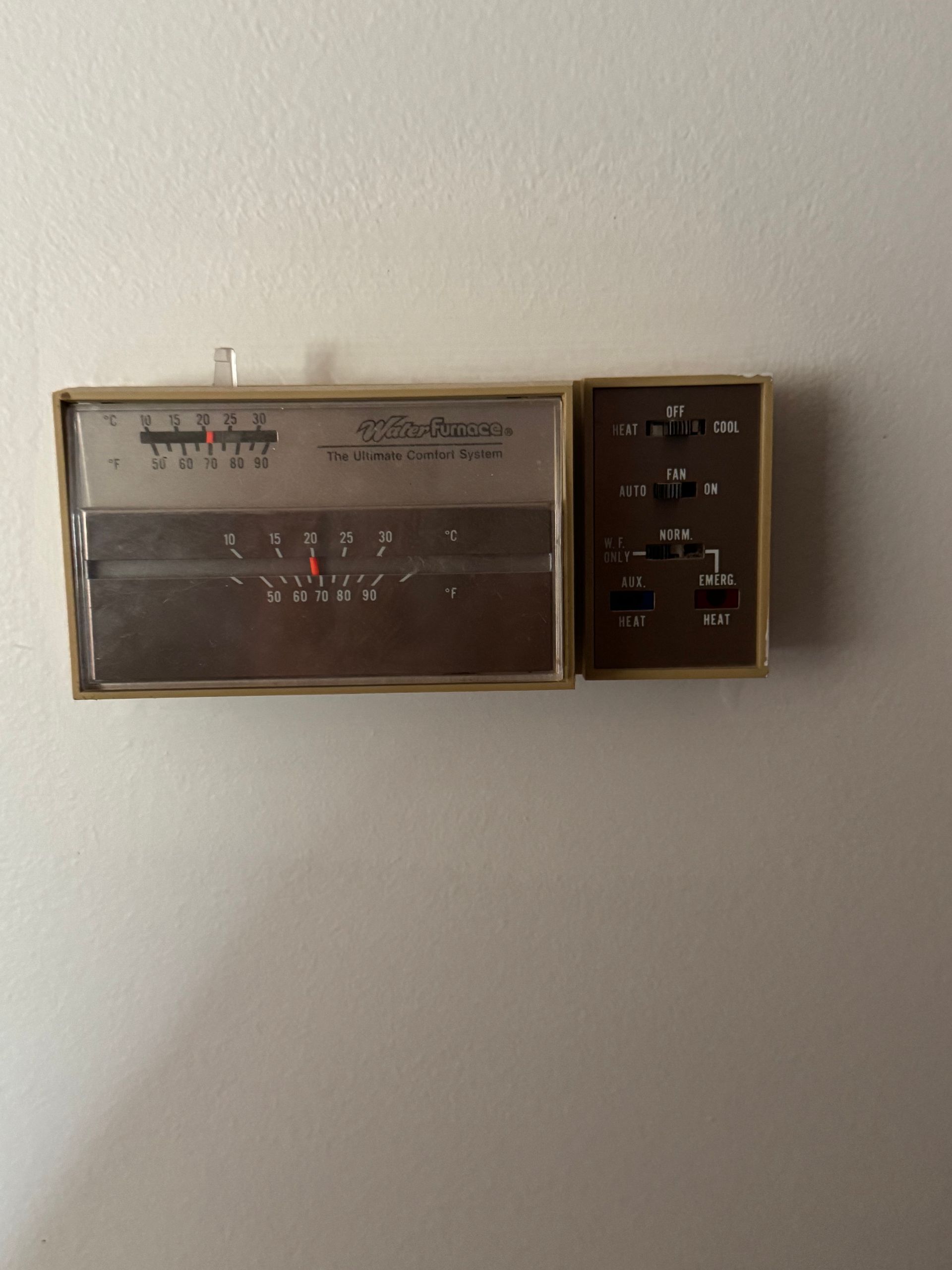 A thermostat is hanging on a white wall