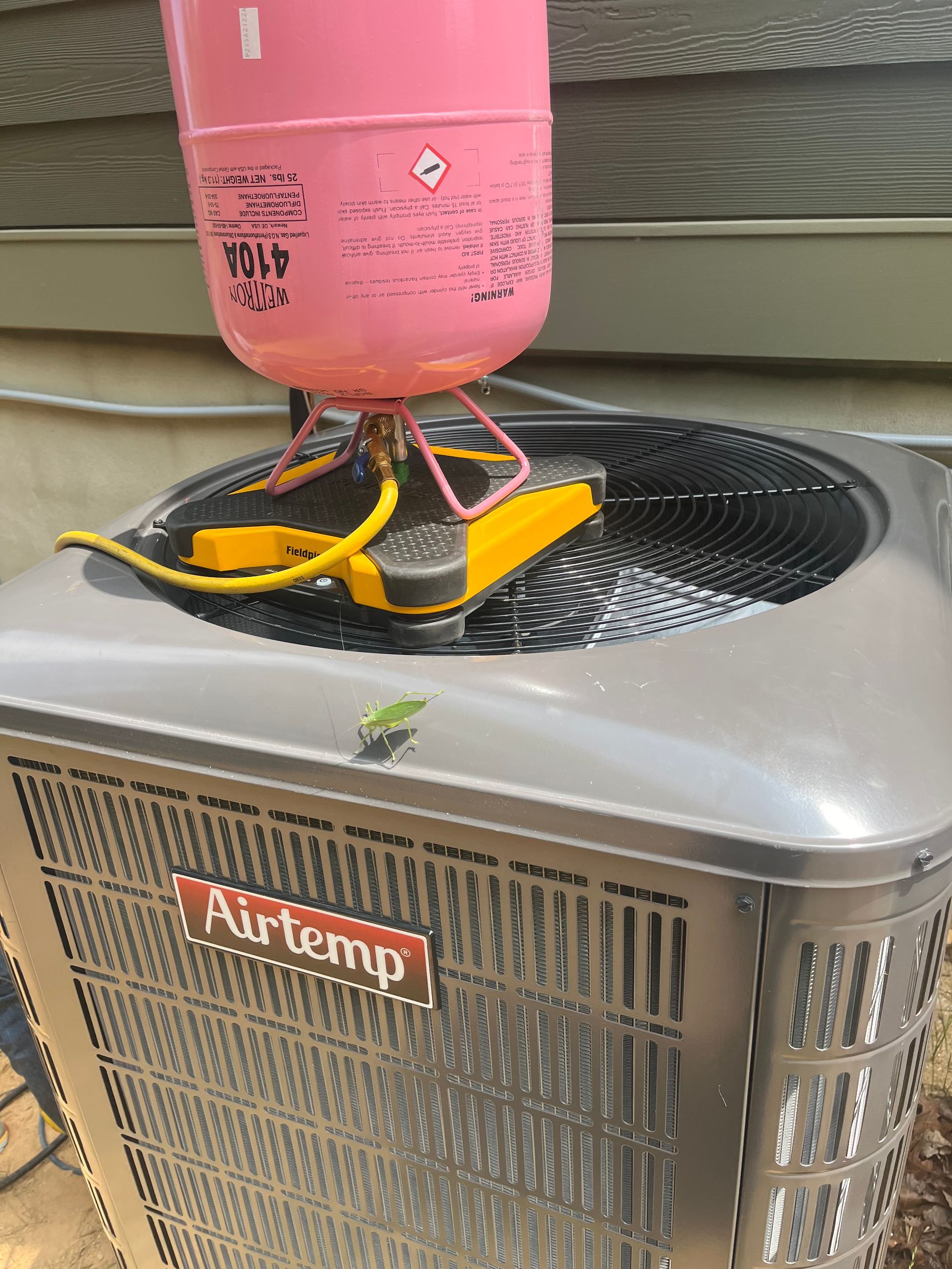A propane tank is sitting on top of an air conditioner.