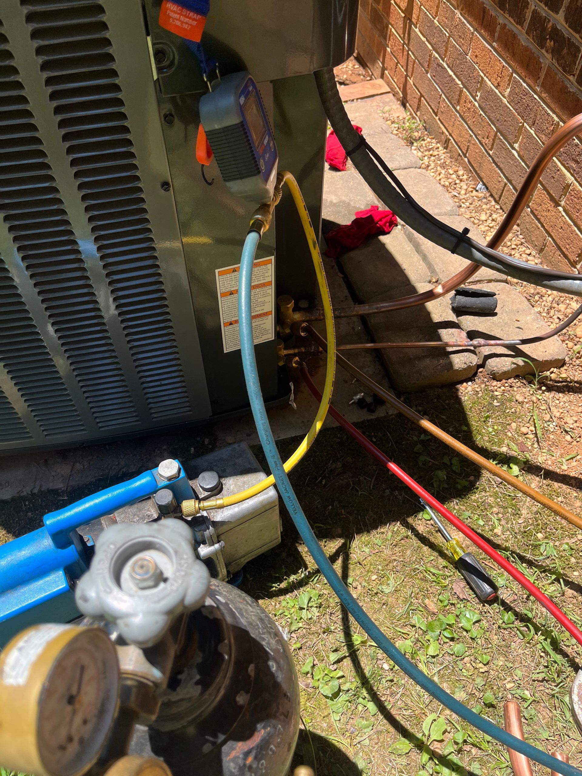 A person is working on an air conditioner outside of a brick building.