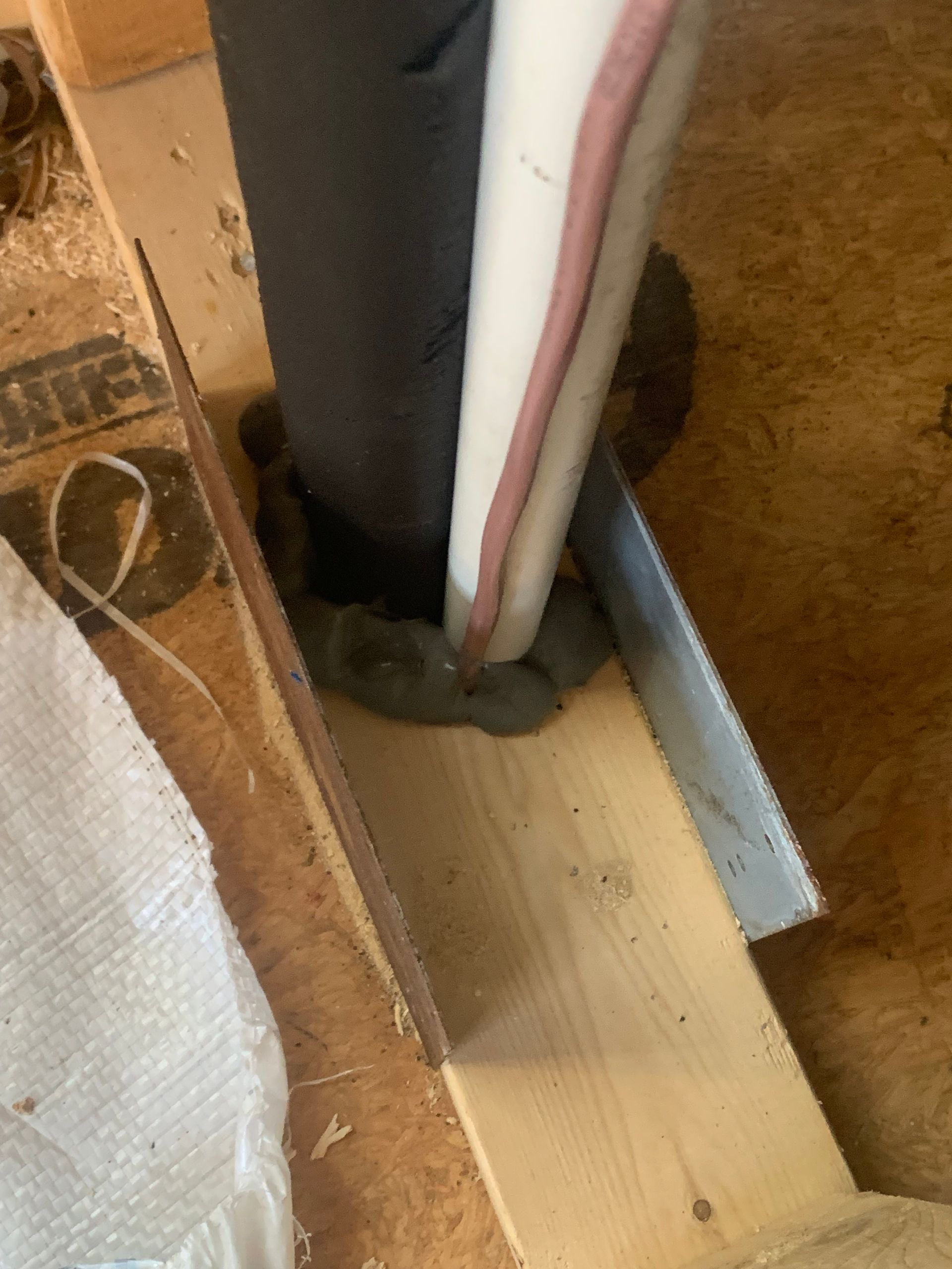 A pipe is being installed on a wooden floor