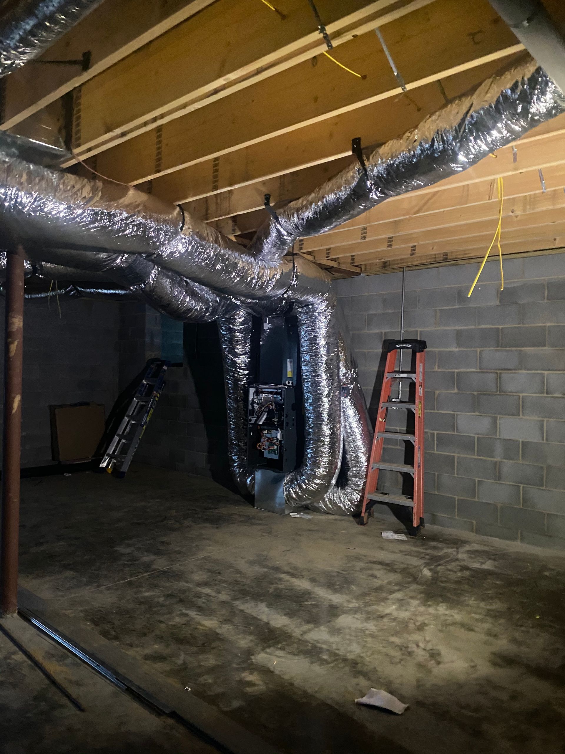 An empty basement with a ladder in the corner