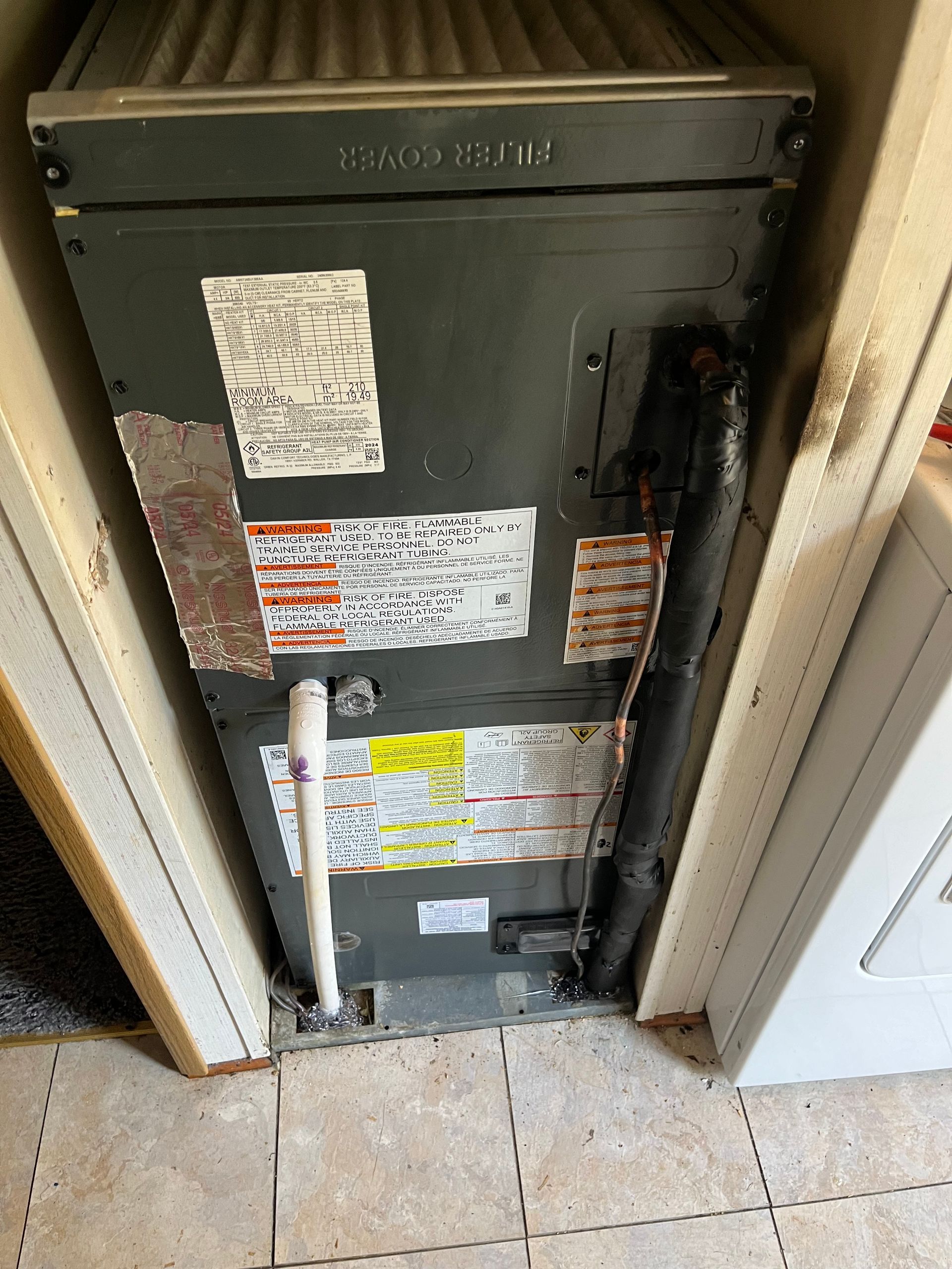 An air conditioner is sitting in a closet next to a washer and dryer.
