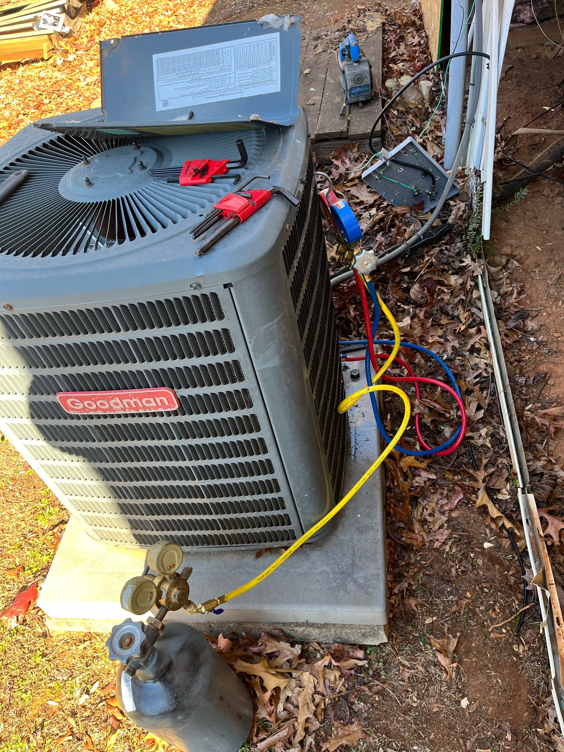 An air conditioner is being repaired on the side of a house.
