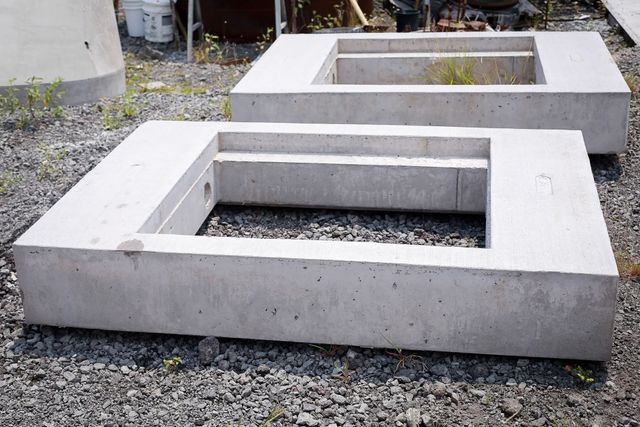 Two concrete rectangular bench frames on a gravel surface outdoors.