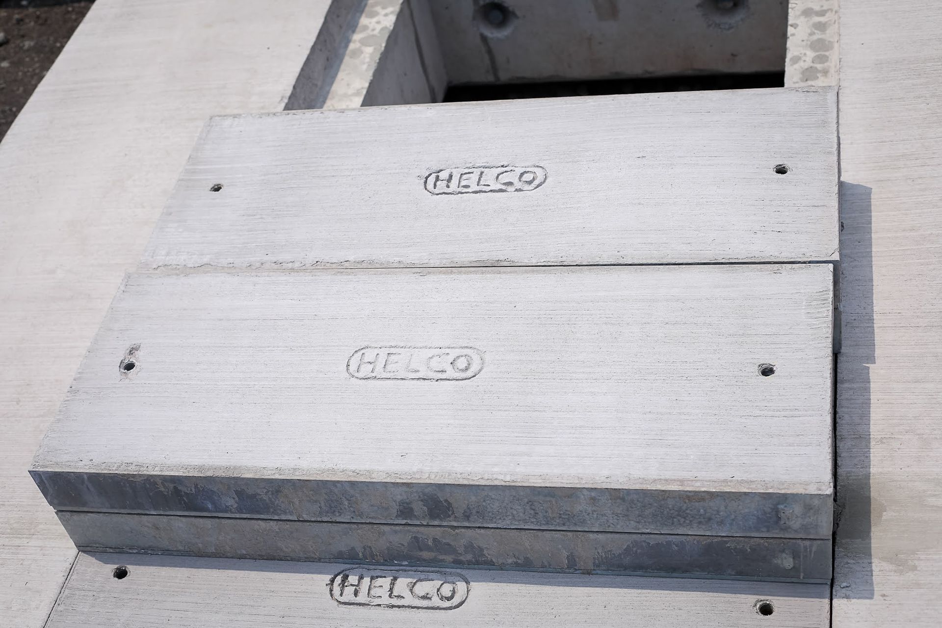 Gray concrete utility box lids with “HESCO” embossed on top, set in a sidewalk.