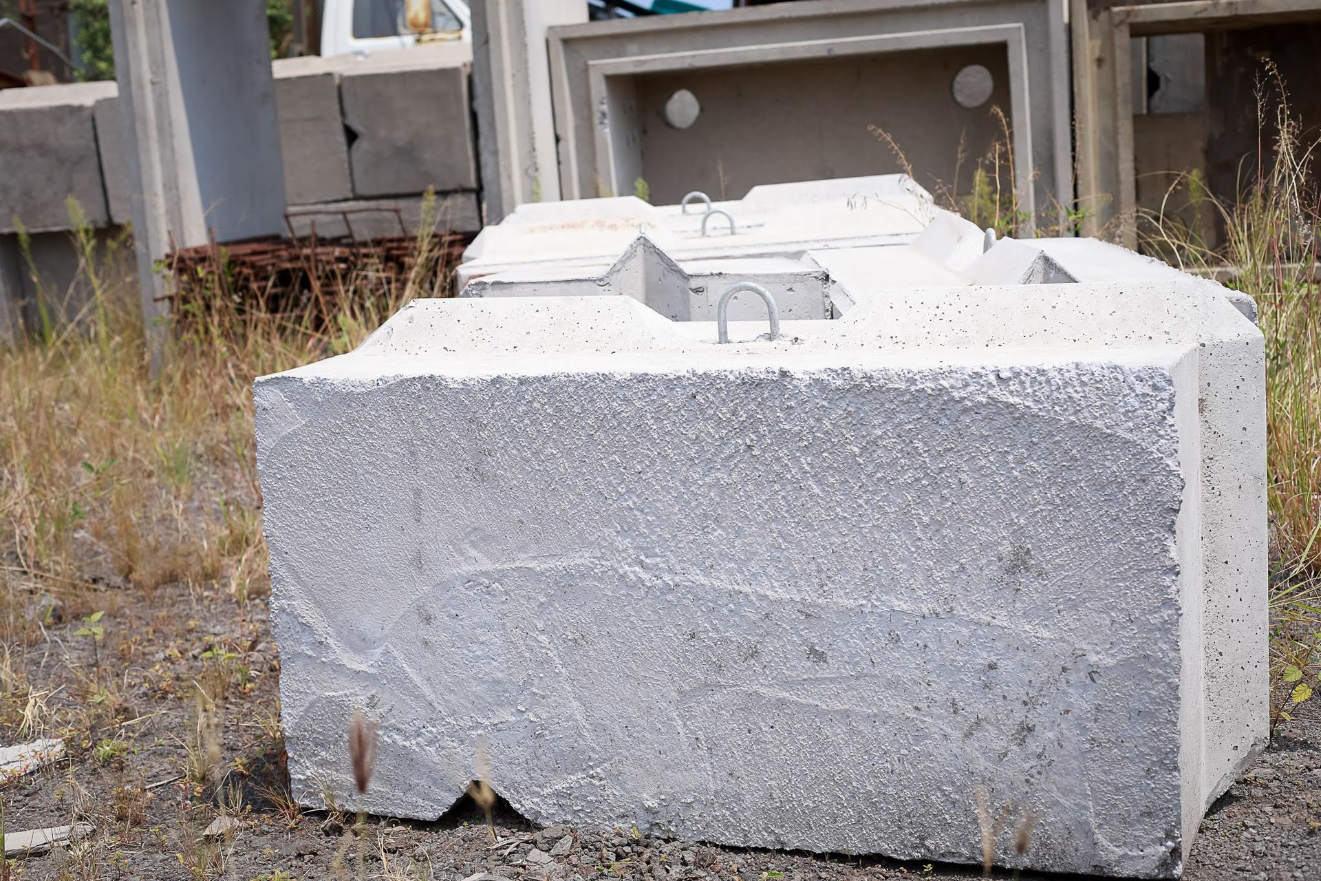 White concrete blocks stacked outdoors in a grassy industrial yard