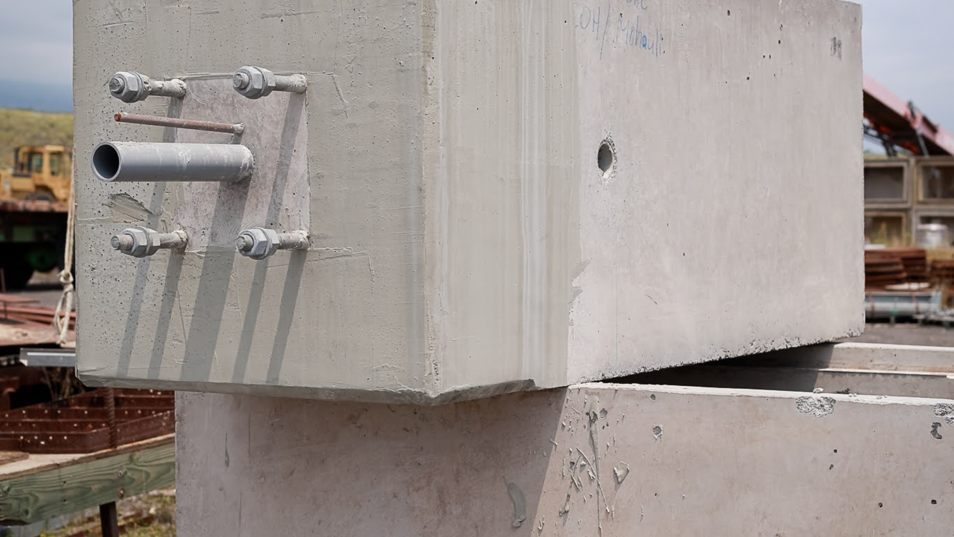Concrete beam connection detail with protruding metal pipes on a construction site