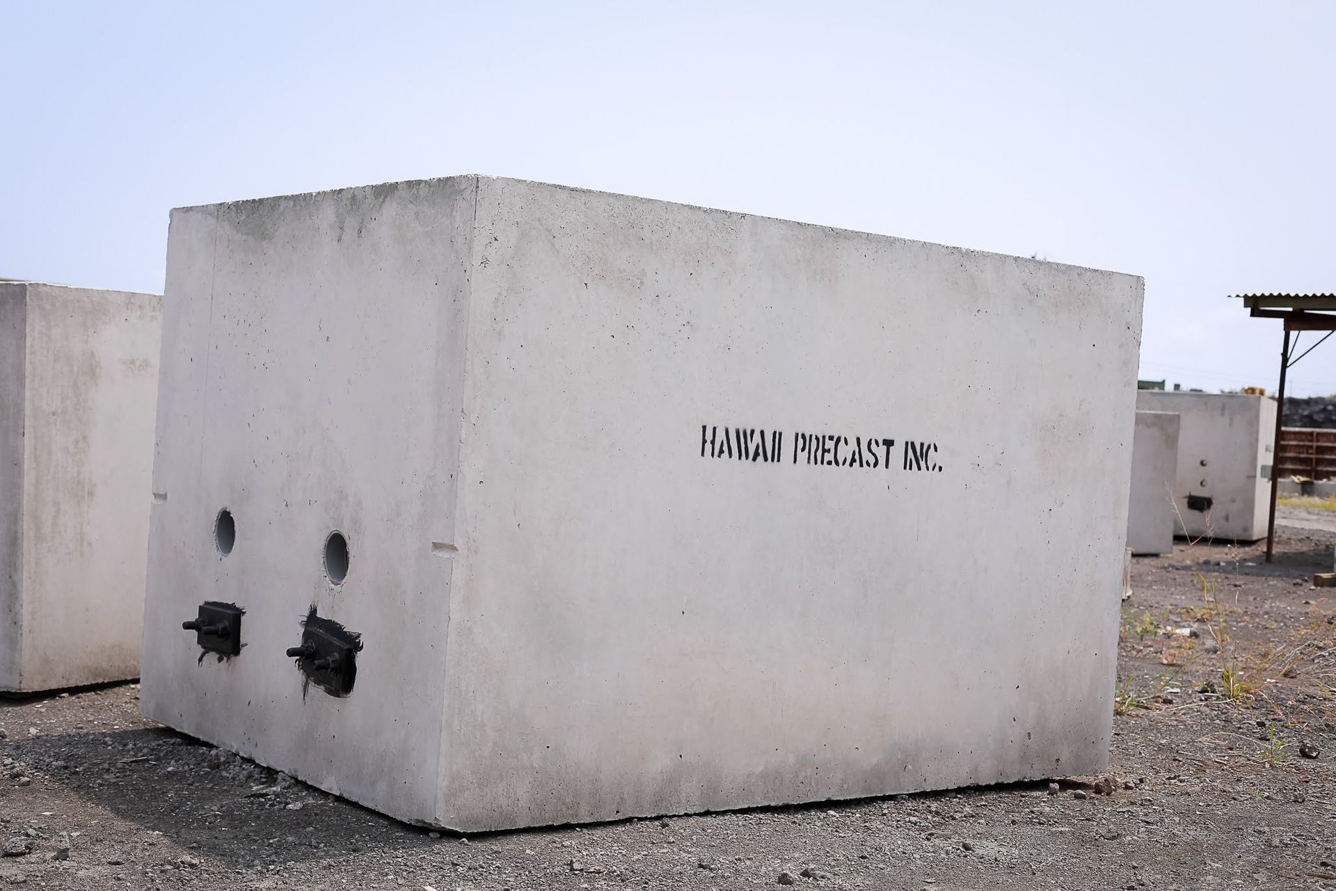White concrete utility block with black valve fixtures in a gravel lot
