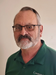 Man with glasses and mustache wearing a green shirt, looking at the camera.