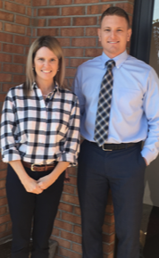 A man and a woman are posing for a picture in front of a brick building