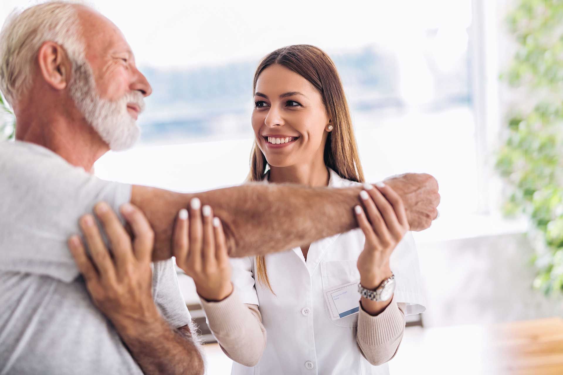 A nurse helping an elderly man with his arm exercises