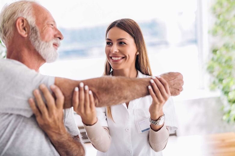 A nurse helping an elderly man with his arm exercises
