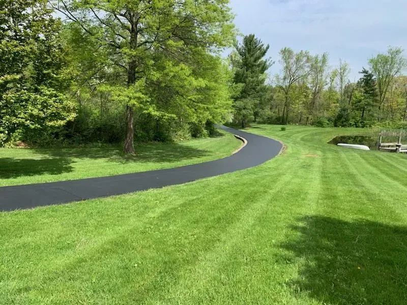 Winding paved path through a green park with trees and manicured grass on a sunny day