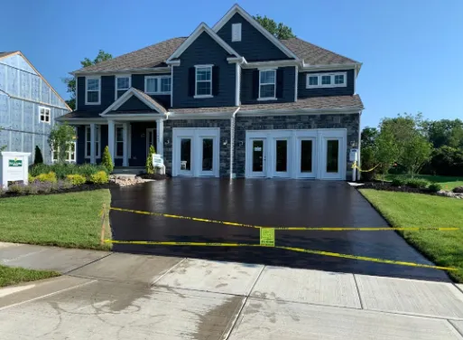 Blue two-story house with a dark driveway, yellow caution tape, and a garage in a suburban neighborhood