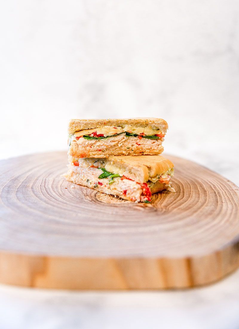 A panini is sitting on top of a wooden cutting board