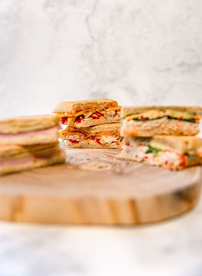 A bunch of paninis on a wooden cutting board
