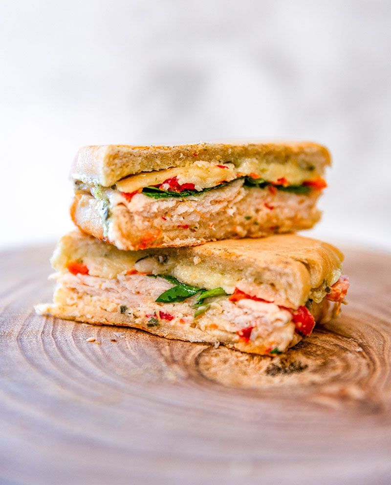 Two paninis are stacked on top of each other on a wooden cutting board