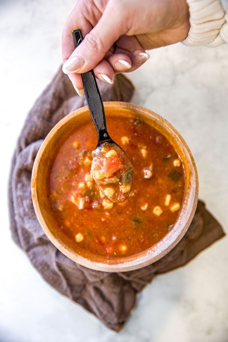 A person is holding a spoon in a bowl of soup