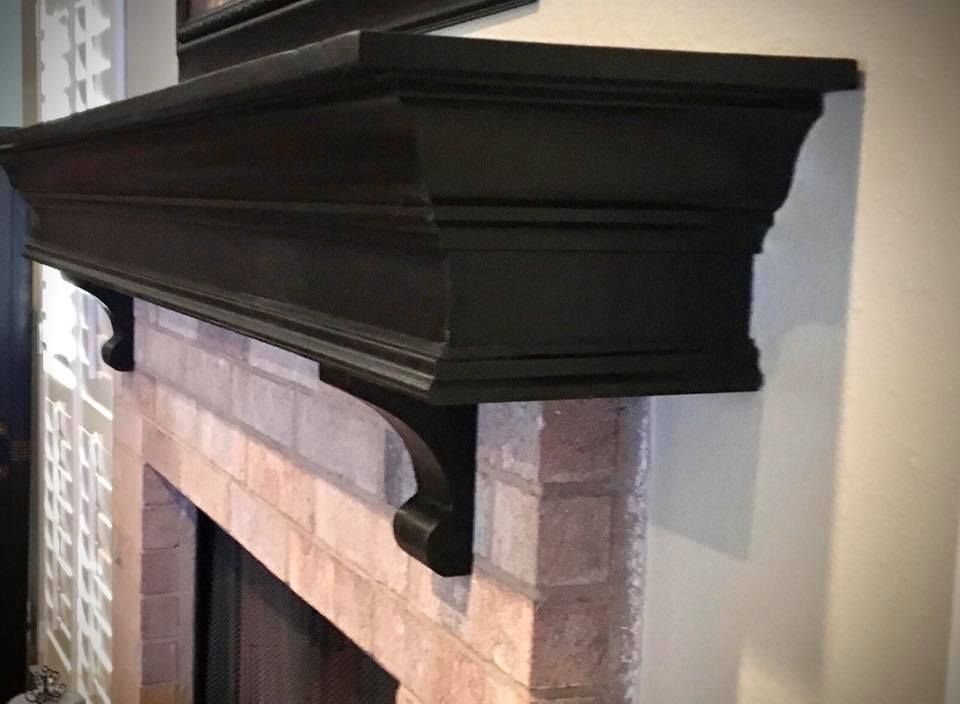 Black fireplace mantel over a brick fireplace.