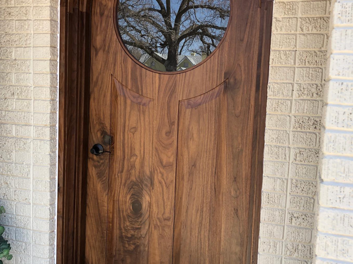 Wooden front door with circular window, set in brick.